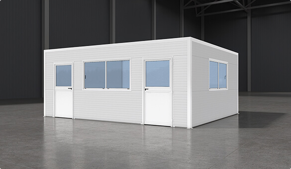 White modular prefabricated room with doors and windows placed inside large industrial warehouse with polished concrete floor and steel beams.